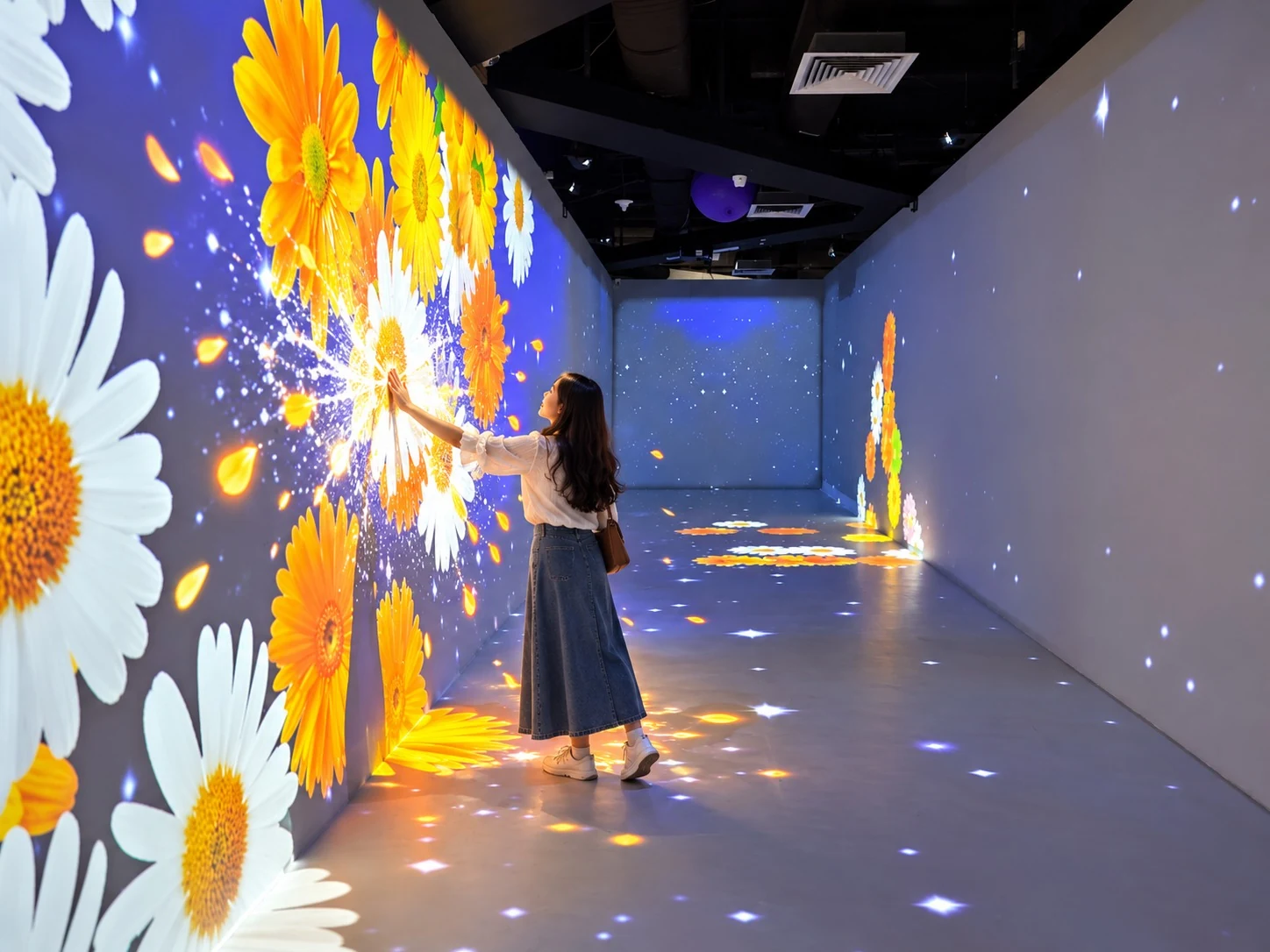 Visitor touching a colourful flower projection in The Tunnel